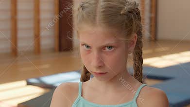 Angry girl looking at camera close up sad frustrated offended child kid pupil student annoyed schoolgirl in gym upset