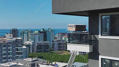 Aerial View: A mechanical lift raises heavy furniture to upper floors through a balcony on-site.