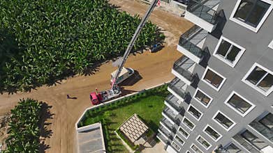 Aerial View: Workers use a mechanical lift to transport furniture through a balcony to high floors.
