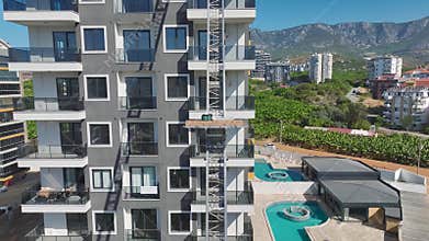 Aerial View: Workers operate a lift to transport furniture through a balcony to the highest floors.