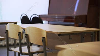 Classroom features rows of desks and chairs with piano at front