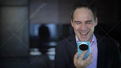 Businessman texting on his mobile phone sitting entering data with his thumbs and concentrating on the screen