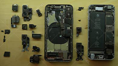 Disassembled and broken smartphones, along with internal components, displayed on wooden board. Concept complexity and