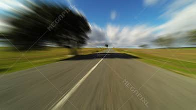 Fast driving car on the road in green fields