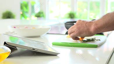 Close Up Of Man Following Recipe On Digital Tablet