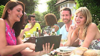 Friends Having Barbeque At Home Looking At Digital Tablet