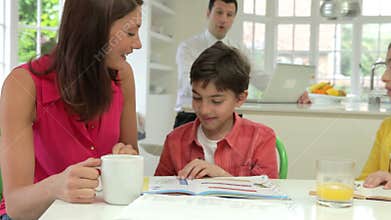 Mother Helping Children With Homework As Father Uses Laptop