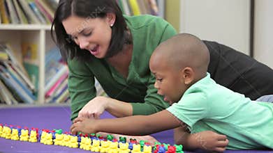Teacher Showing Boy How To Count With Plastic Toys