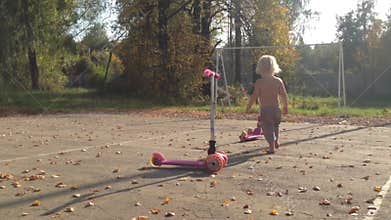 Toddler Exploring with Pink Scooters in Autumn Park