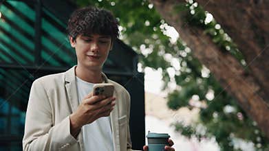 Portrait of young businessman reading message on smartphone on city street