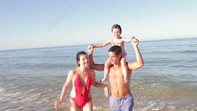 Father Carrying Daughter On Shoulders As Family Run Out Of Sea