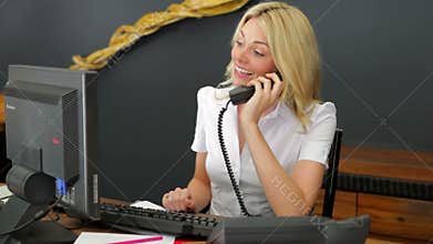 Hotel Receptionist Using Computer And Phone