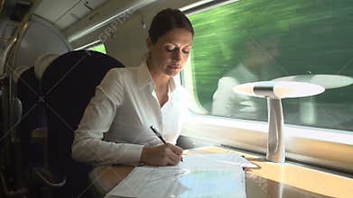 Female Commuter On Train Working On Document