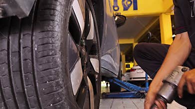 A skilled mechanic uses a power tool to change a tire, ensuring safety and maintenance