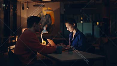 Two programmers tired overtime work at dark workplace. Fatigued workers evening