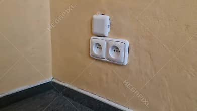 Slow motion close-up of two newly installed electrical outlets and a cable cover on apricot orange wall in an empty room