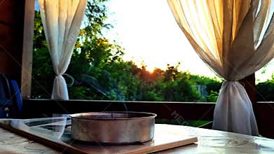 Summer veranda at sunset with smoke and fluttering curtains.