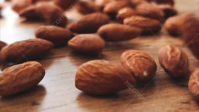 A close-up video shot of sliced almonds slowly pouring onto a wooden table, creating a natural and appetizing pile.