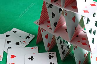 House of playing cards on green background, closeup