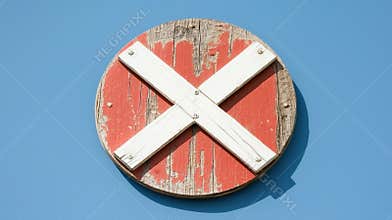 A weathered wooden sign with a red cross on a blue background.