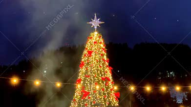Large Christmas tree with red bows and string lights at night