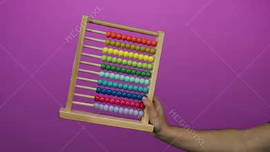 Caucasian man holding colorful abacus against vibrant pink background, emphasizing education and learning tools