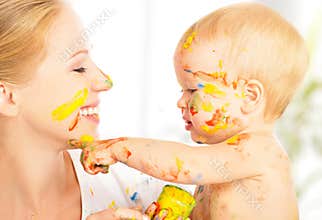 Happy dirty baby draws paints on her face of mother
