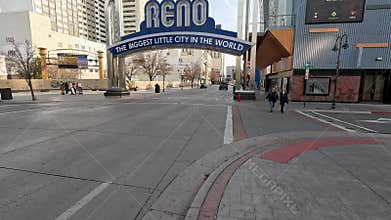The Reno Arch with hotels and casinos and cars driving along the street at sunset in Reno Nevada