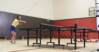 Playing table tennis, woman and man competing in indoor sports facility