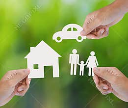 Hand holding paper home, car, family on green background