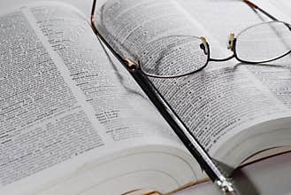 Open book with glasses and pen