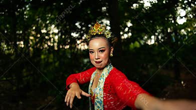 a traditional Balinese dancer wearing a red costume which is a symbol of cultural preservation with beautiful motifs while in the