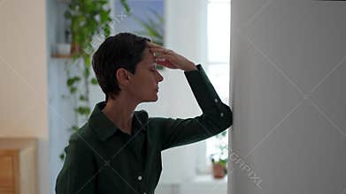 Exhausted tired mature woman rubbing forehead, battling migraine and mental fatigue at home alone