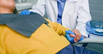 Dentist Comforts Anxious Patient by Holding Her Hand During Dental Procedure, Showing Empathy and Care