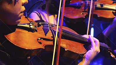 wo violinists performing on stage under blue concert lighting