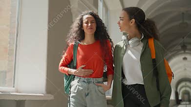 Two students girl Hispanic women Latina female friends in university college walking talking woman feeling stomach ache