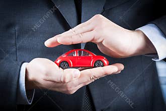 Businessman protect with his hands a red car, concept for insurance, buying, renting, fuel or service and repair costs