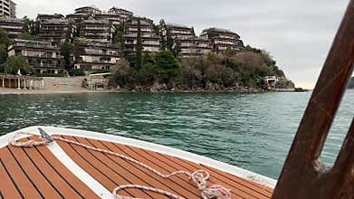 View from a wooden boat approaching modern coastal buildings