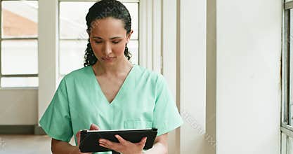Young Nurse Checks Patient Information on Tablet While Walking Down Hospital Hallway