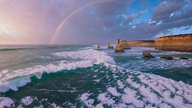 Rainbow over the twelve apostles rock formations on coastline with waves at sunset, great ocean road australia. Scenic
