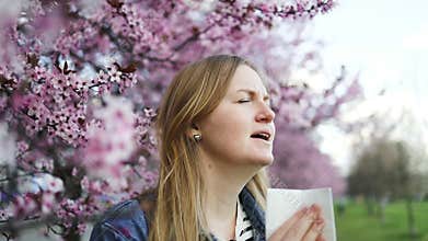 Woman experiencing allergy symptoms under cherry blossoms in spring