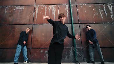 Redheaded breakdancer performing dynamic street dance moves with two crew members near contemporary urban setting