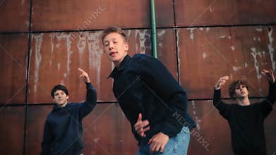 Street performers executing dynamic choreography, sharing powerful dance movements near weathered metal wall