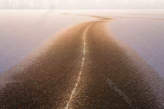 Frosty sunny morning, golden road on the ice lit by the morning sun