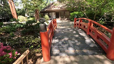 footage of an arched orange bridge over a river, lush green trees and flowers at Descanso Gardens La Canada Flintridge California