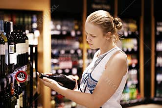 Woman reading inscription on the wine bottle in