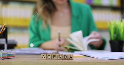 Businesswoman sits at desk and writes down key points for Agenda
