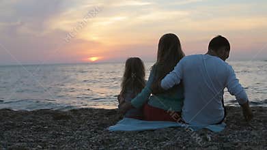 Family with little daughter sitting near the sea