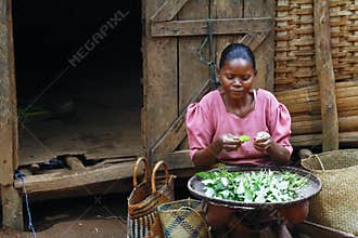 Poor Malagasy woman preparing food in front of cabin