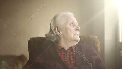 Portrait of an old lonely human who looks out the window